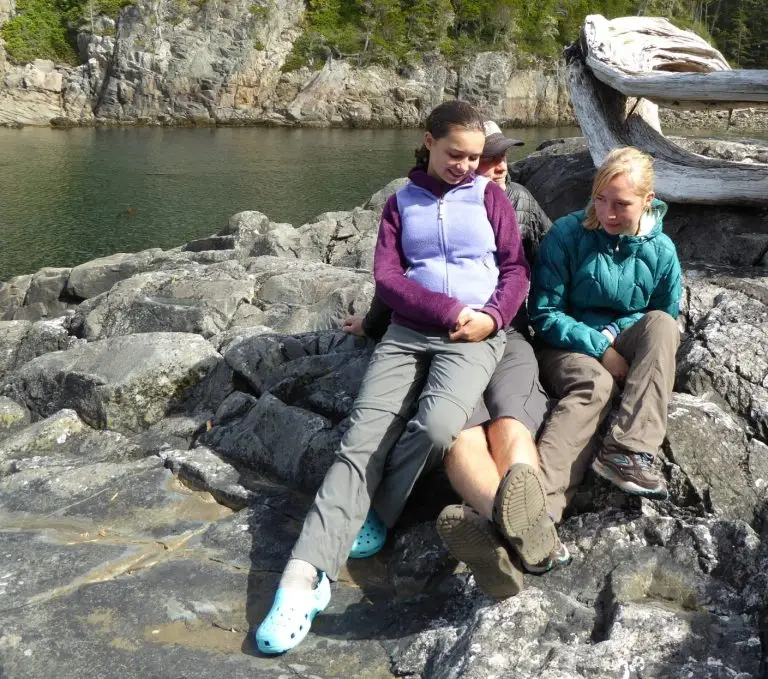Dad and daughters sitting on a rock