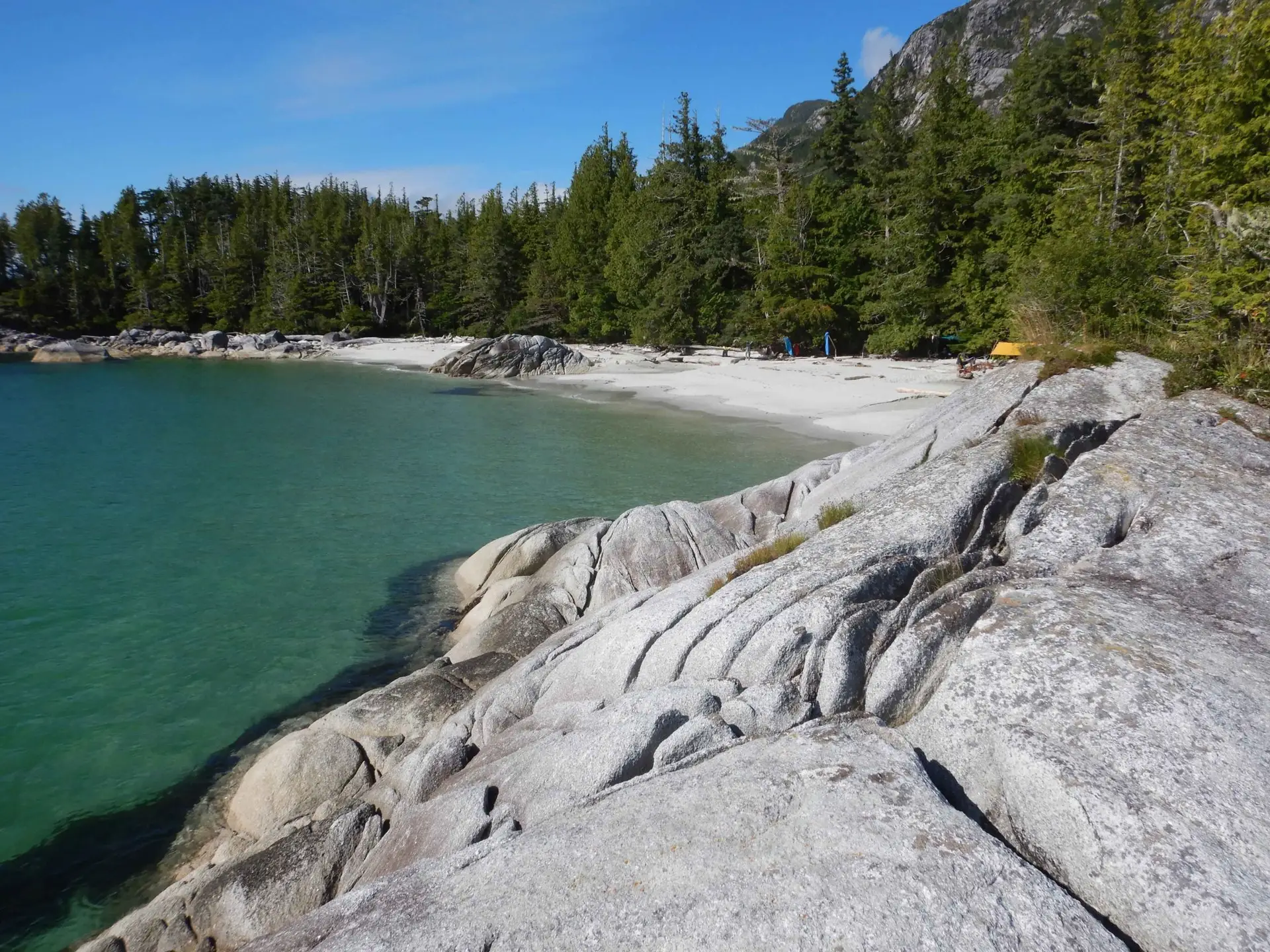 sandy beach and campsite with rocks in the foreground