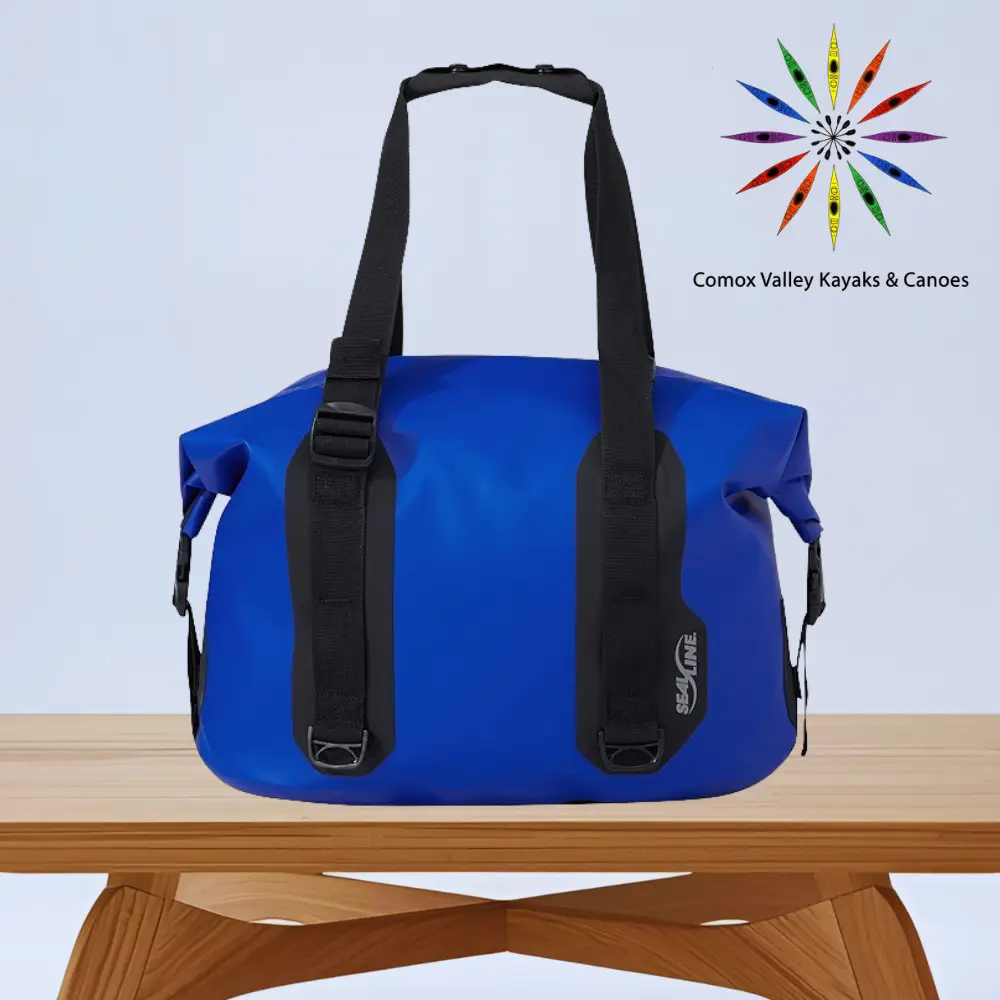 Blue waterproof duffel bag with black straps on a wooden table.