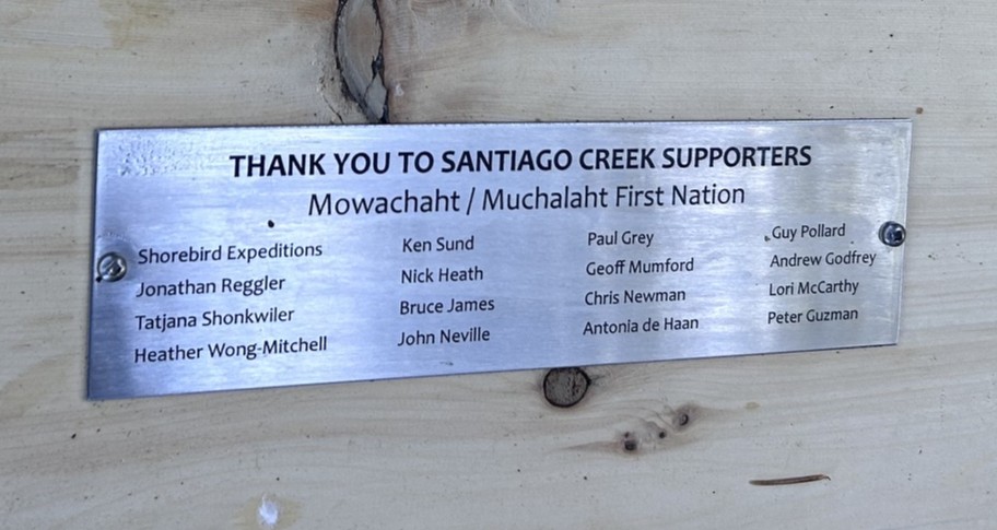 Metal commemorative plaque mounted on wood listing supporters for Mowachah / Muchalah First Nation, with many names engraved