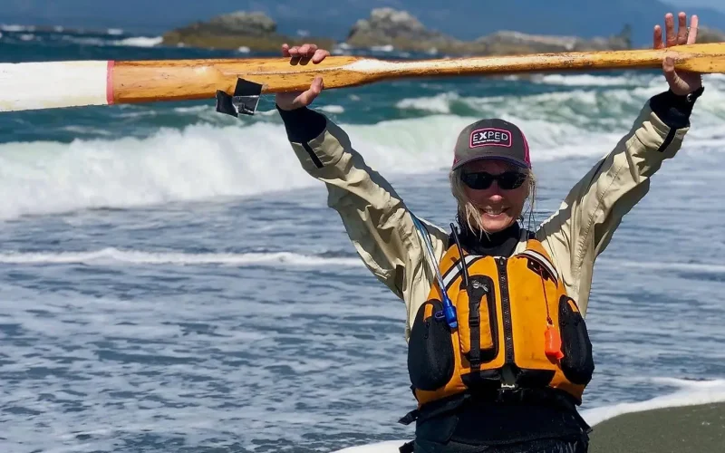 woman standing with a paddle overhead